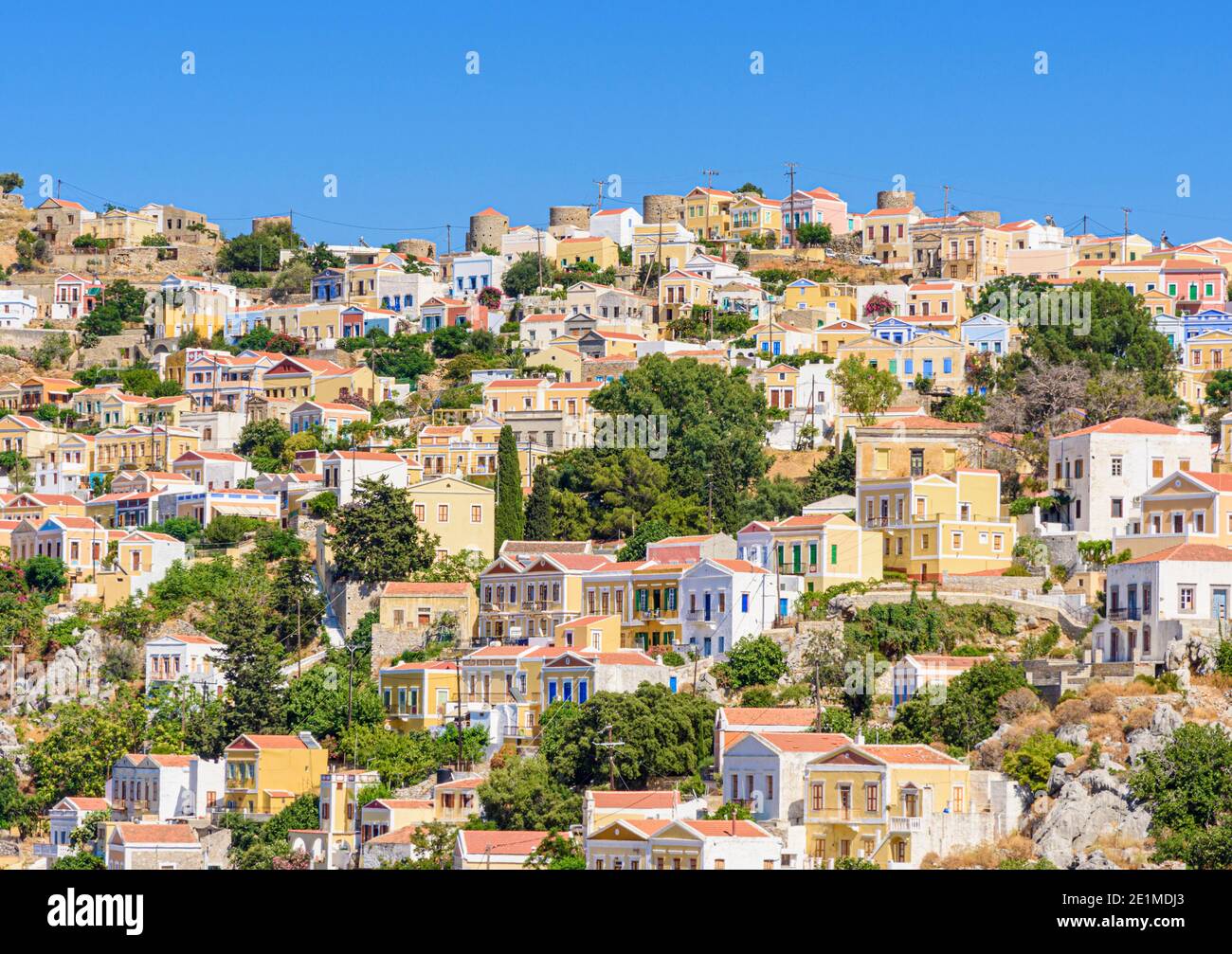 Vecchi mulini a vento in cima alla collina e palazzi neo-classici della vecchia collina Horio, Symi Island, Dodecanese, Grecia Foto Stock