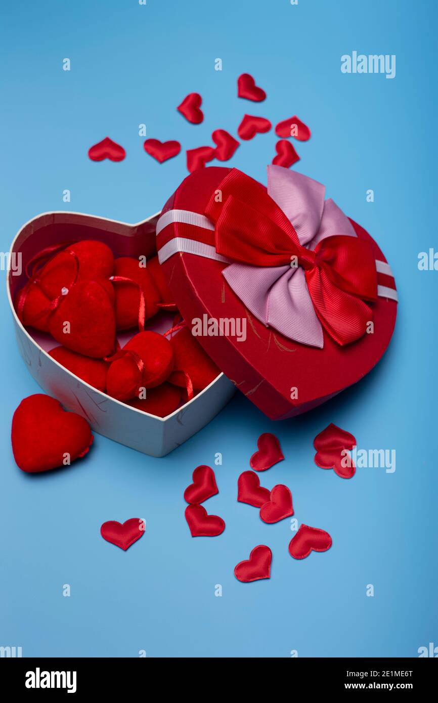 Scatola regalo a forma di cuore piena di cuori su sfondo blu. Buon giorno  di San Valentino. Immagine verticale Foto stock - Alamy