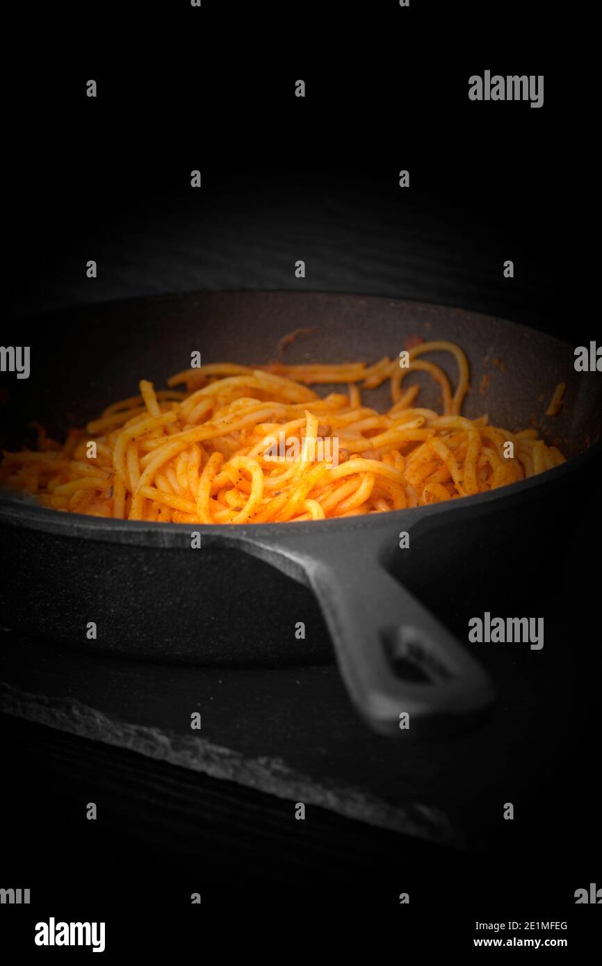 Spaghetti bolognesi cotti in una padella di ghisa. Con effetto di illuminazione Foto Stock