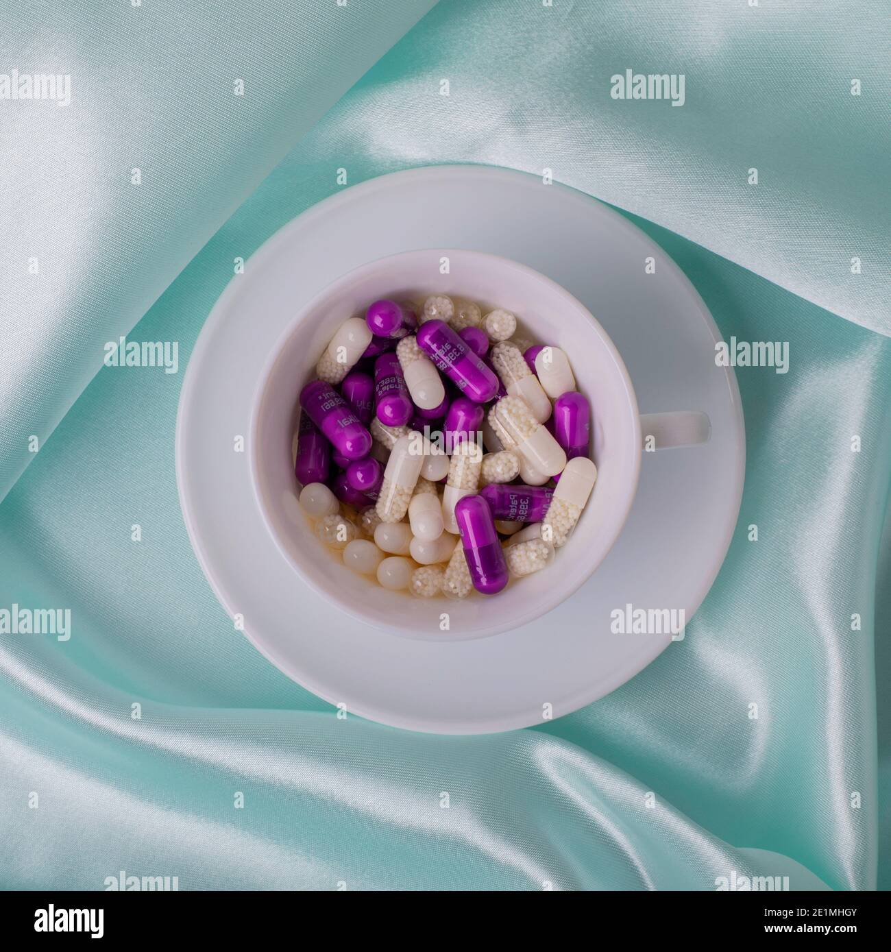 Caffè a letto riempito con pillole su raso blu. Droga di dipendenza Foto Stock