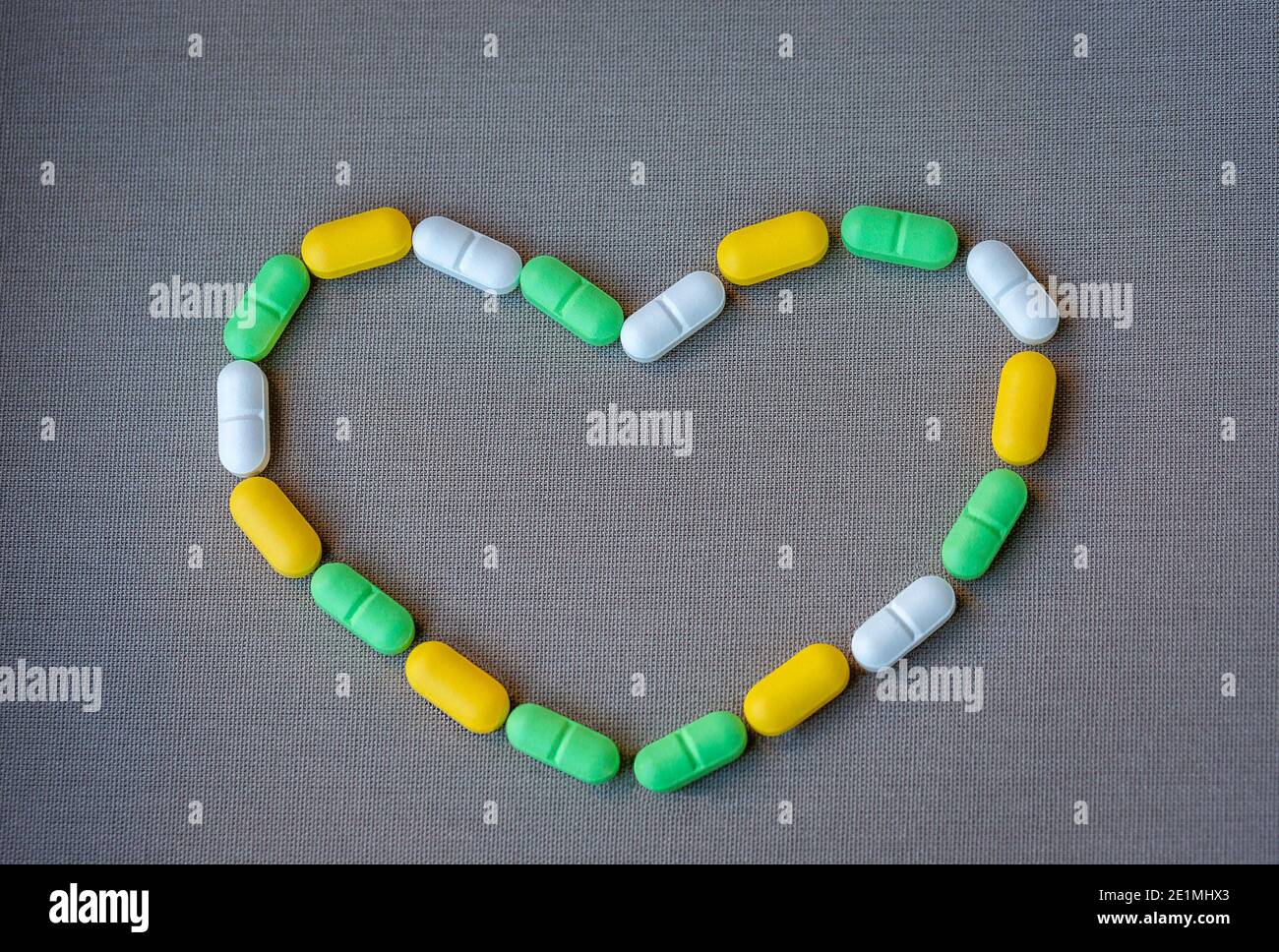 Forma del cuore fatta da pillole di diversi colori per la terapia delle malattie cardiache, concetto di assistenza sanitaria. Spazio per il testo. Foto Stock