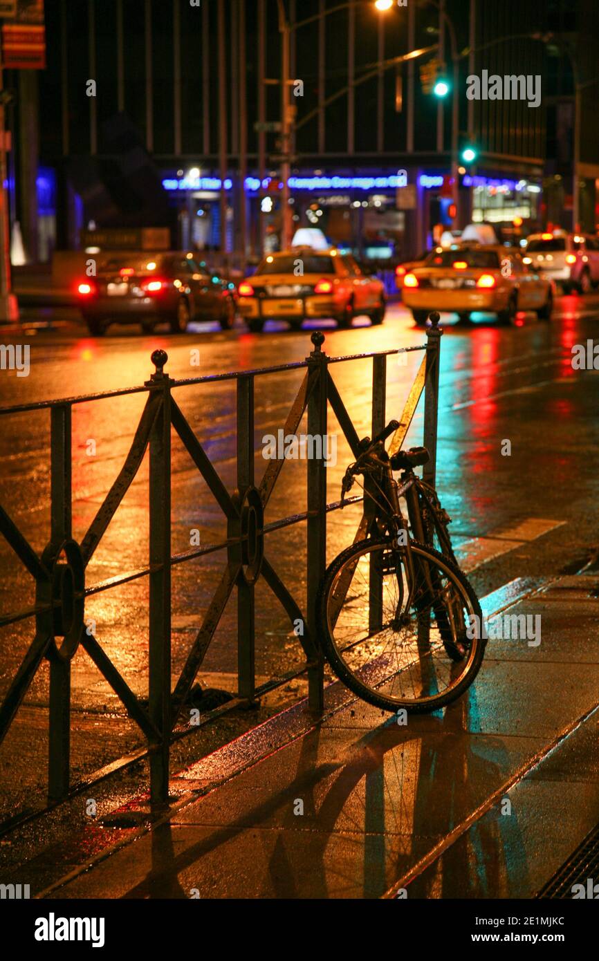 Scena di strada notturna di New York con bicicletta che conduce ai taxi gialli in lontananza. NEW YORK, STATI UNITI Foto Stock