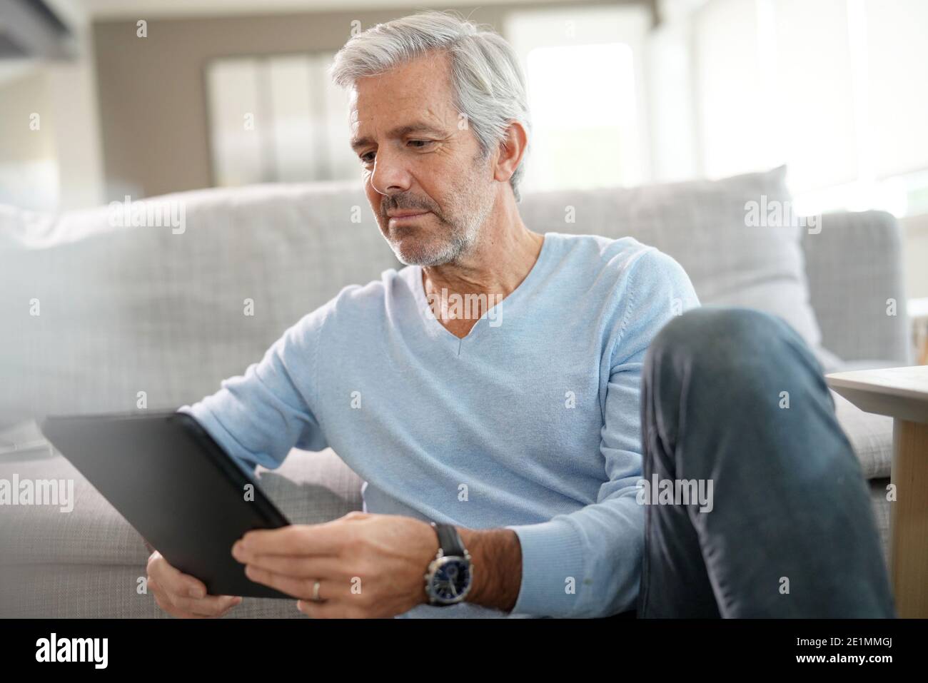 uomo di 60 anni a casa connesso a un tablet digitale Foto stock - Alamy