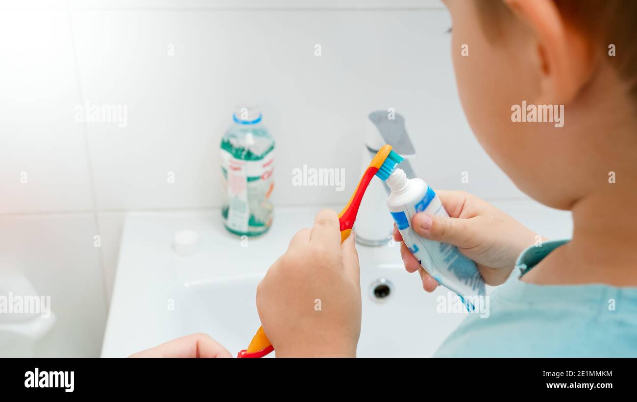 Bambino che applica il dentifricio sullo spazzolino in bagno Foto Stock