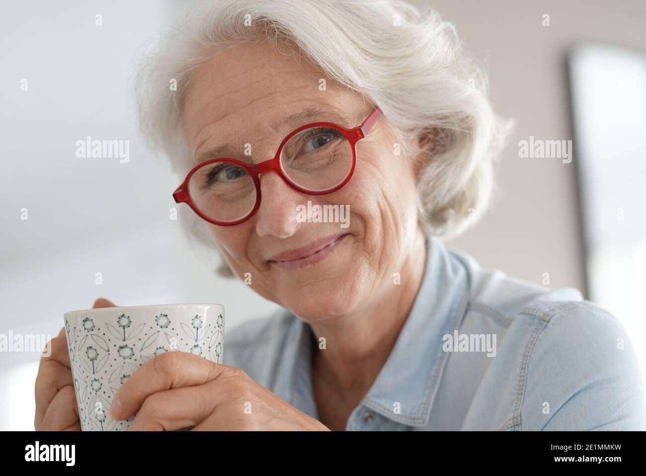 Donna anziana sorridente con occhiali rossi Foto Stock
