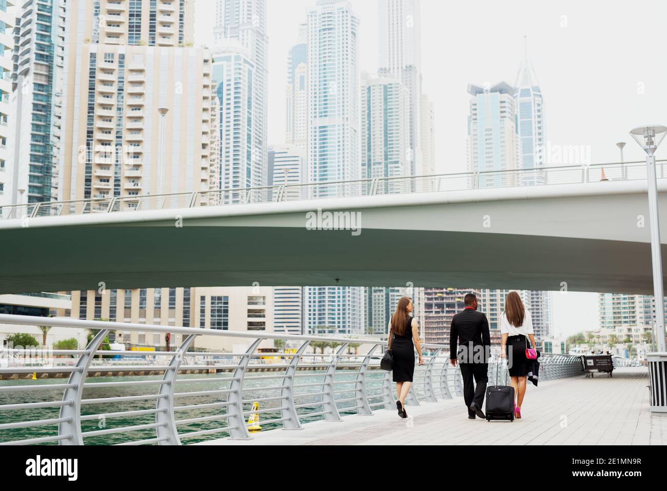 I college d'affari che camminano attraverso Dubai Marine dopo aver finito il lavoro per quel giorno. Gruppo di afro-americani e due donne europee. Foto Stock