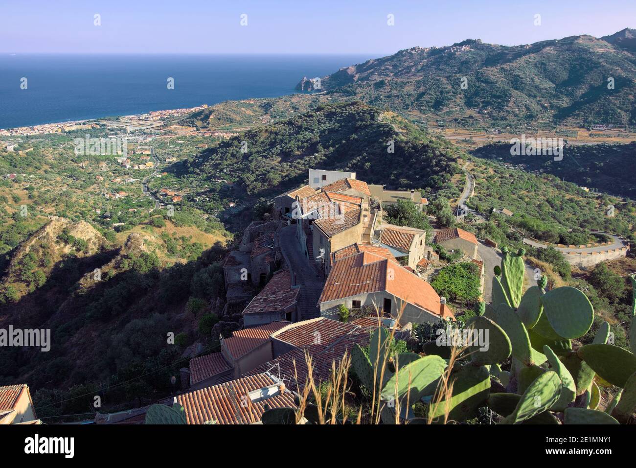 Vista sulla costa orientale della Sicilia dalla città di Savoca sulle colline siciliane, tetti in tegole, paesaggio collinare coperto di vegetazione e mare blu Foto Stock