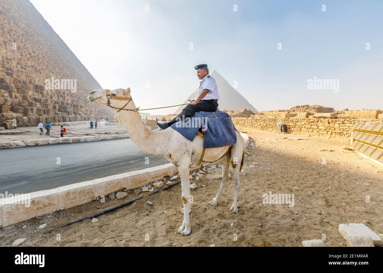 Poliziotto locale montato su un cammello nel complesso della Piramide di Giza (necropoli di Giza) di fronte alla Piramide di Khafre, il Cairo, Egitto Foto Stock