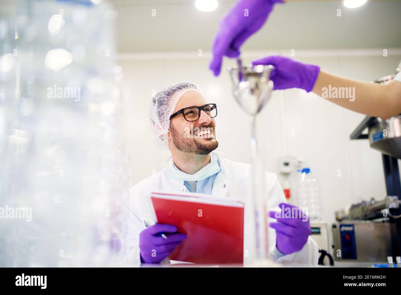 Allegro dipendente di laboratorio che prende nota degli esperimenti di test. Foto Stock