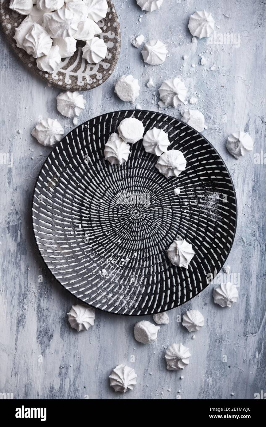 un sacco di meringhe bianche su belle lastre di ceramica, su rustico fondo di legno, nessuno Foto Stock