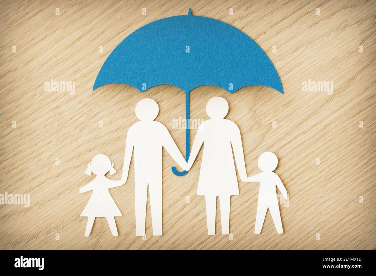 Silhouette famiglia in carta con ombrello su sfondo in legno - concetto della protezione della famiglia Foto Stock