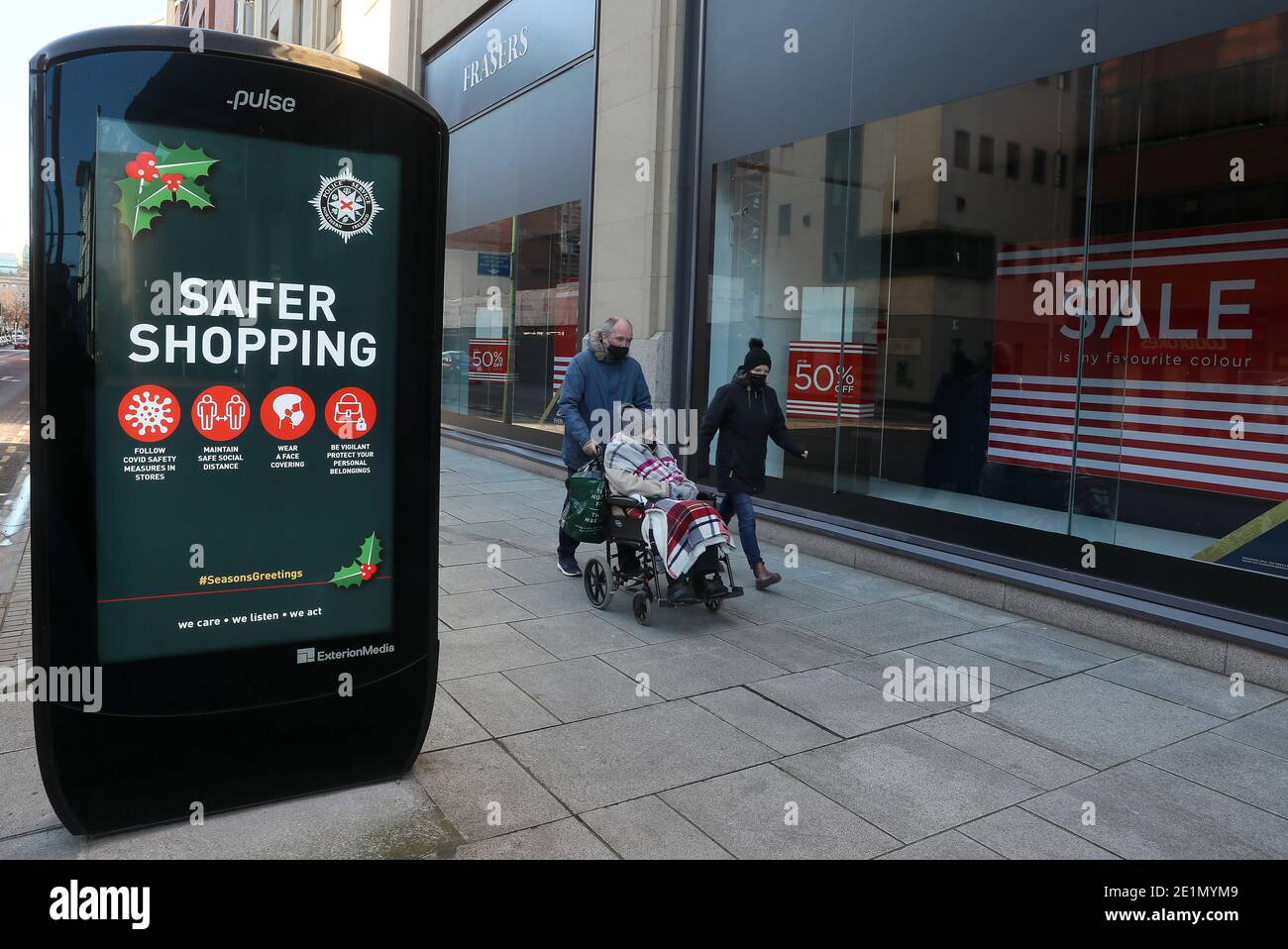 La gente cammina oltre un annuncio per l'operazione di saluti di stagione di PSNI su una strada tranquilla nel centro di Belfast, come il blocco di sei settimane in Irlanda del Nord continua. Foto Stock