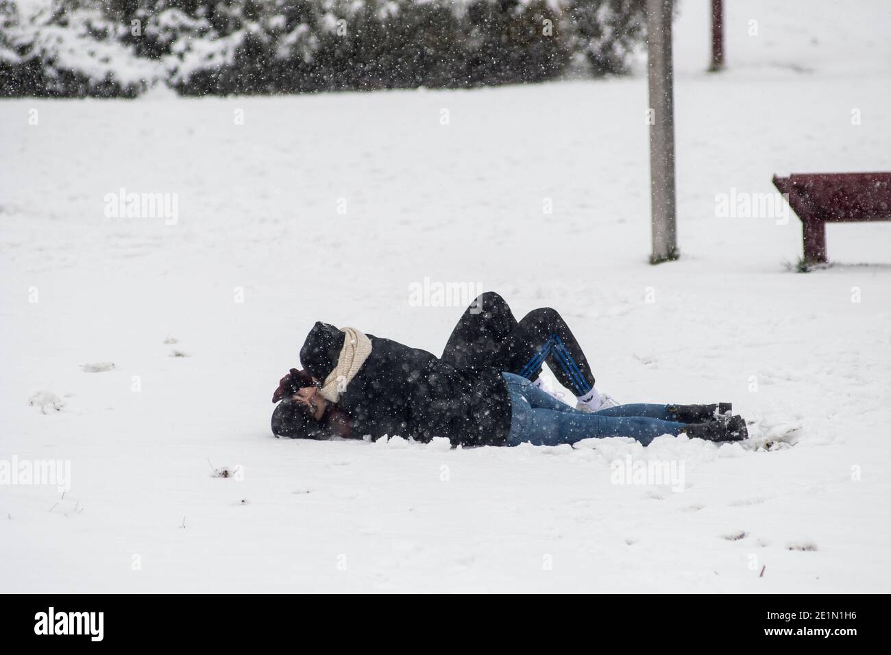 Madrid, Spagna. 8 gennaio 2021. Un bacio di coppia sdraiato nella neve mentre la neve cade in un parco di Madrid. Un avvertimento è stato emesso in tutto il paese a causa della tempesta 'Filomena' che ha causato un grande calo delle temperature e delle nevicate in tutta la Spagna. Credit: Marcos del Mazo/Alamy Live News Foto Stock
