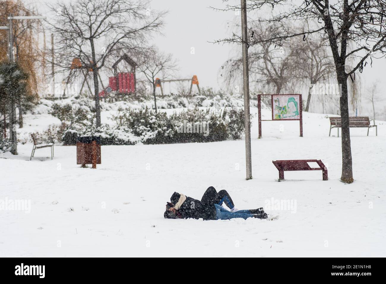 Madrid, Spagna. 8 gennaio 2021. Un bacio di coppia sdraiato nella neve mentre la neve cade in un parco di Madrid. Un avvertimento è stato emesso in tutto il paese a causa della tempesta 'Filomena' che ha causato un grande calo delle temperature e delle nevicate in tutta la Spagna. Credit: Marcos del Mazo/Alamy Live News Foto Stock
