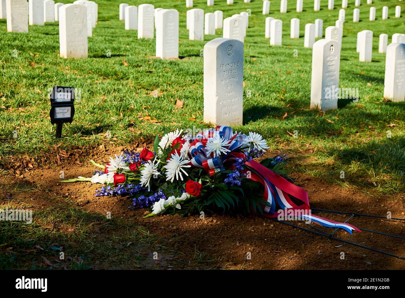 Una corona di nastro rosso, bianco e blu posata su una tomba fresca. Al Cimitero Nazionale di Arlington vicino a Washington DC. Foto Stock