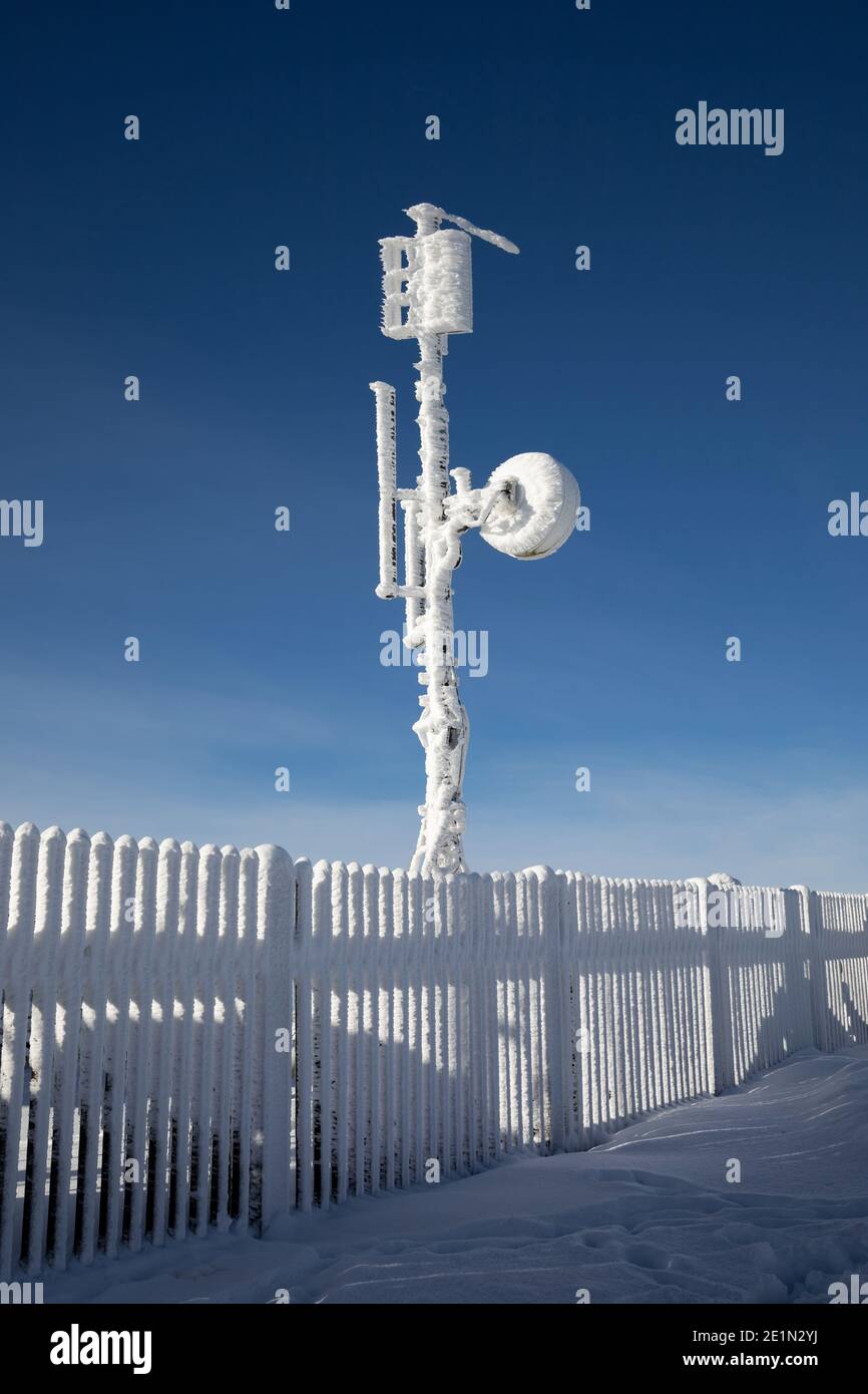 Torre meteorologica con apparecchiature di misurazione, antenna satellitare. Il dispositivo è coperto da neve surgelata, ghiaccio e rime in winte freddo e gelo Foto Stock