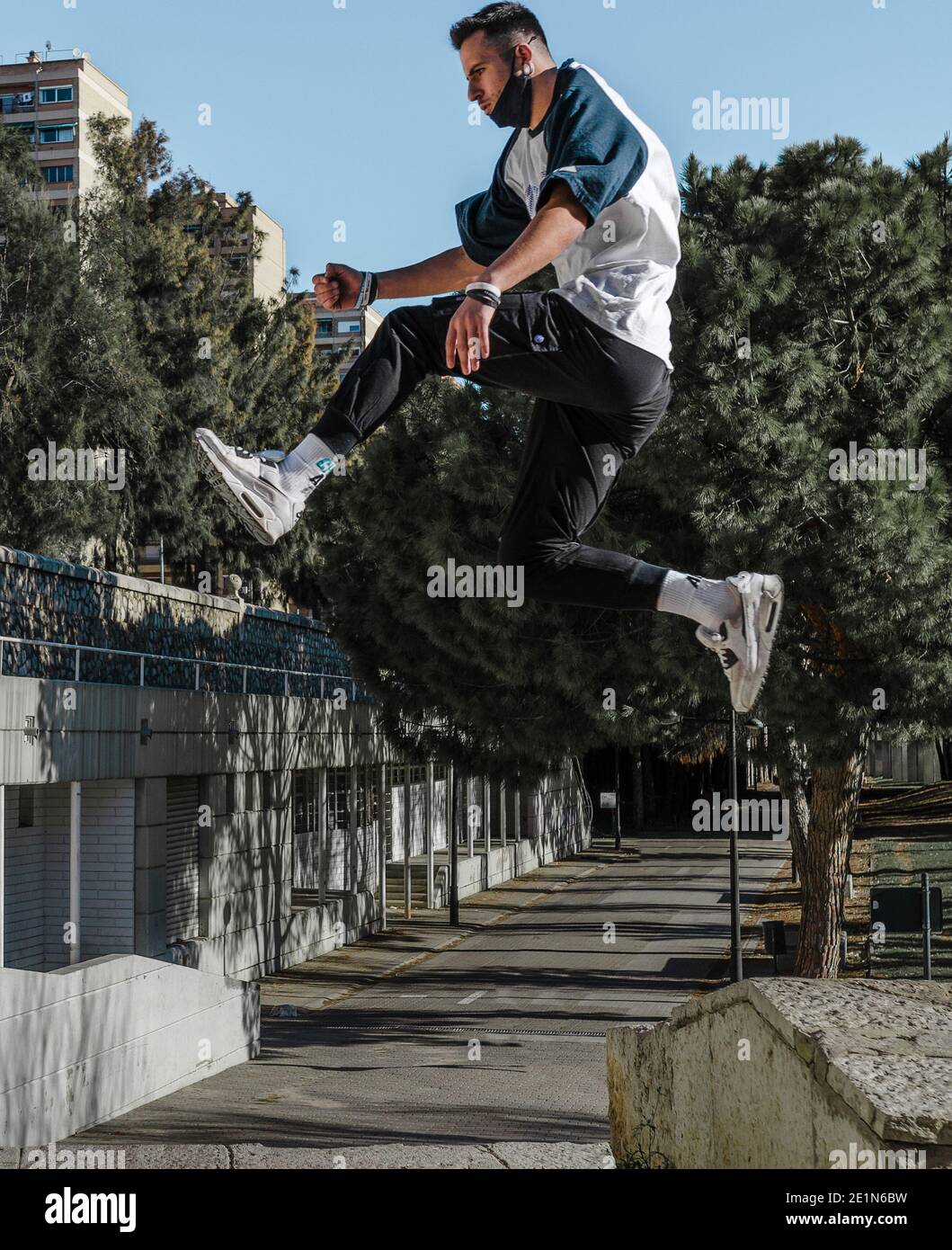 un giovane che salta da un muro in un parco urbano. Parco di allenamento. Foto Stock