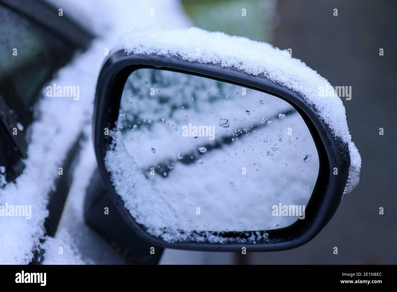 Neve sullo specchio dell'ala dell'auto in seguito alla nevicata durante l'inverno, con riflesso in vetro. Tempo ghiacciato in Irlanda Foto Stock
