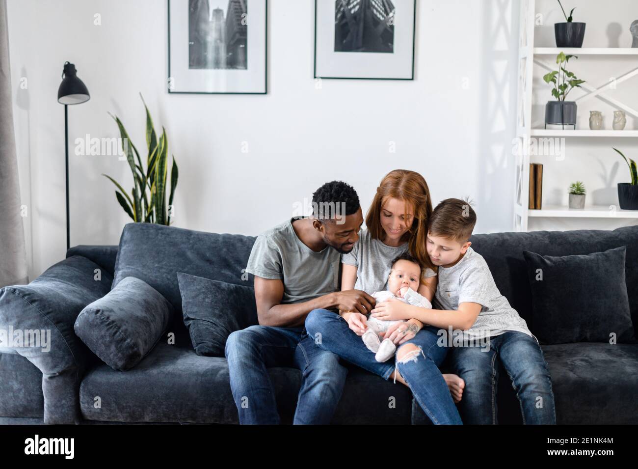 Una famiglia multirazziale si siede sul divano a casa Foto stock - Alamy