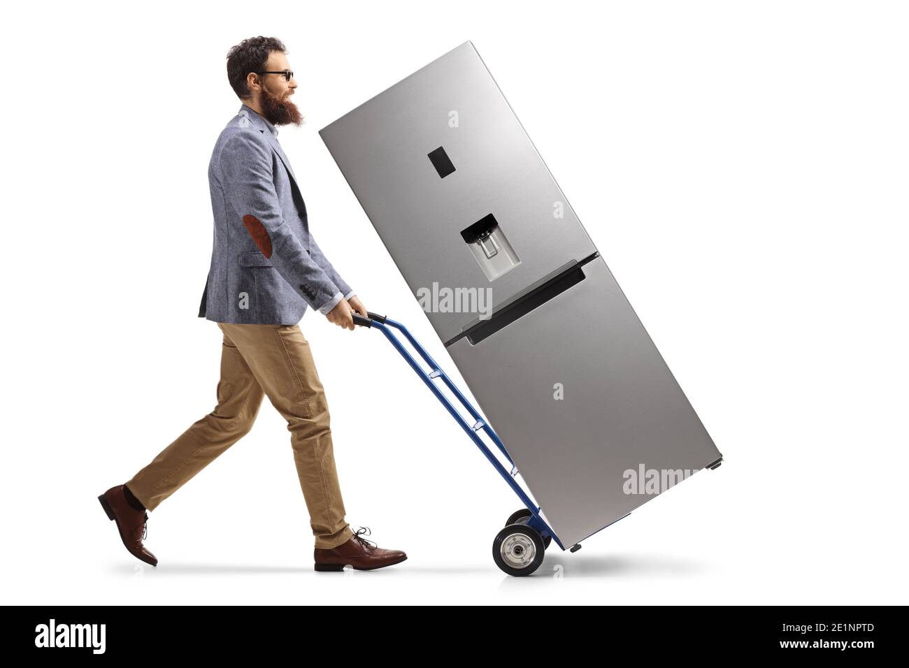 Foto di profilo di lunghezza completa di un uomo bearded che cammina e. spingere un carrello manuale con un frigorifero isolato su bianco sfondo Foto Stock
