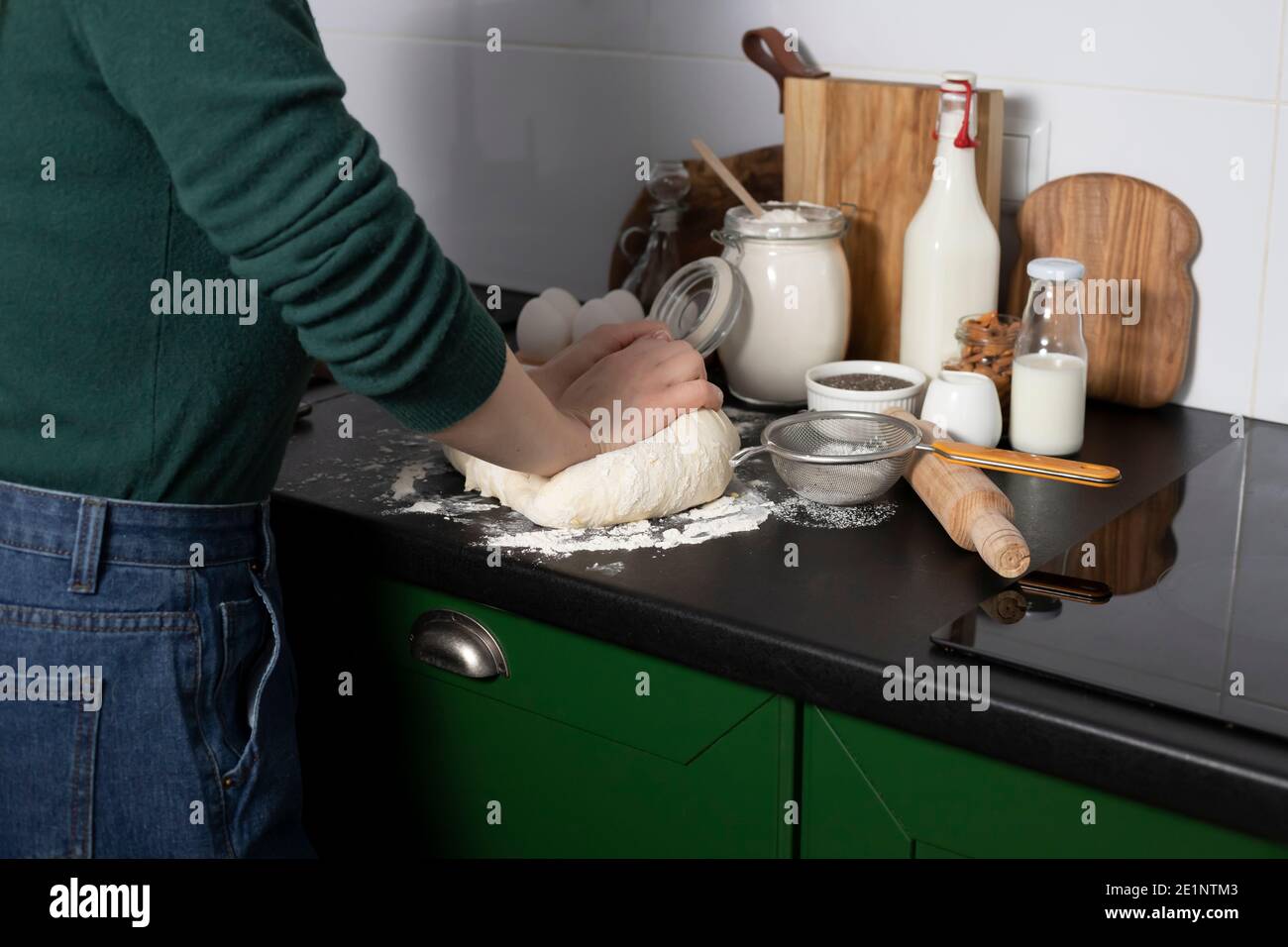 la pasta di lievito pronta per la preparazione di panini fatti in casa è sul tavolo, tra gli altri ingredienti per la cottura del pane. una donna prepara dolci, impasta impasto Foto Stock