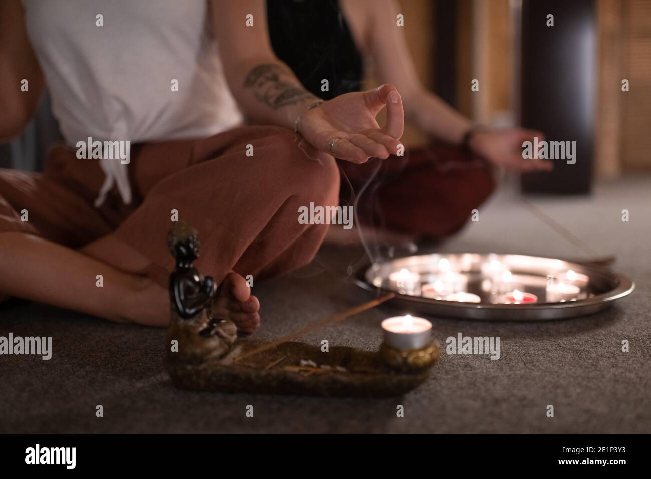 Donna groppata gesturing Gyan mudra durante la meditazione vicino incenso e. candele Foto Stock