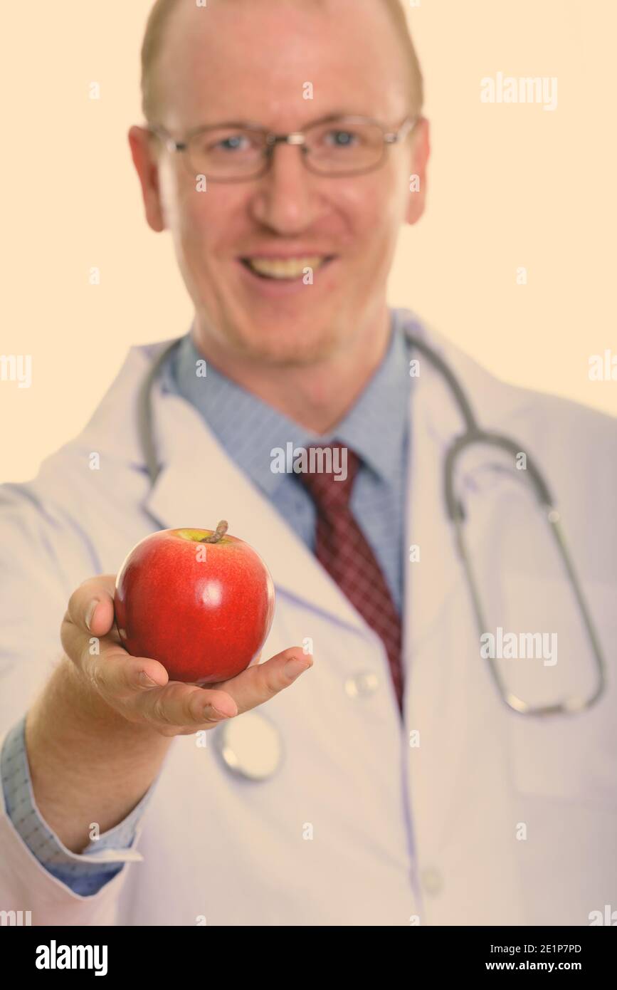Studio shot di uomo felice medico sorridere mentre dando red apple con focus su apple Foto Stock