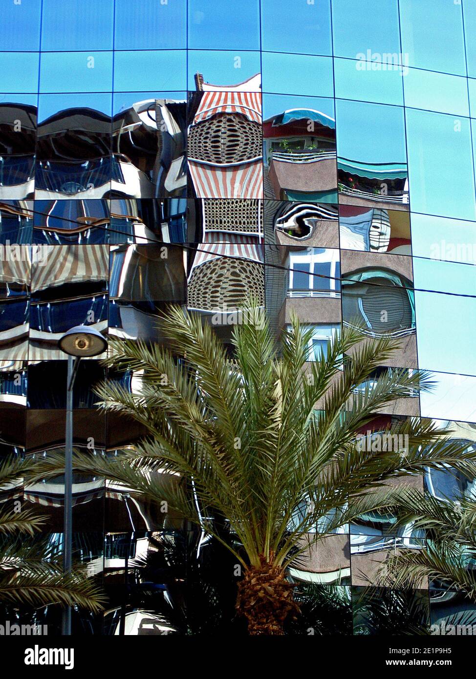 Città di Alicante, Spagna. Riflesso distorto di un edificio nella facciata in vetro riflettente di un altro edificio sul lato opposto della strada. Foto Stock