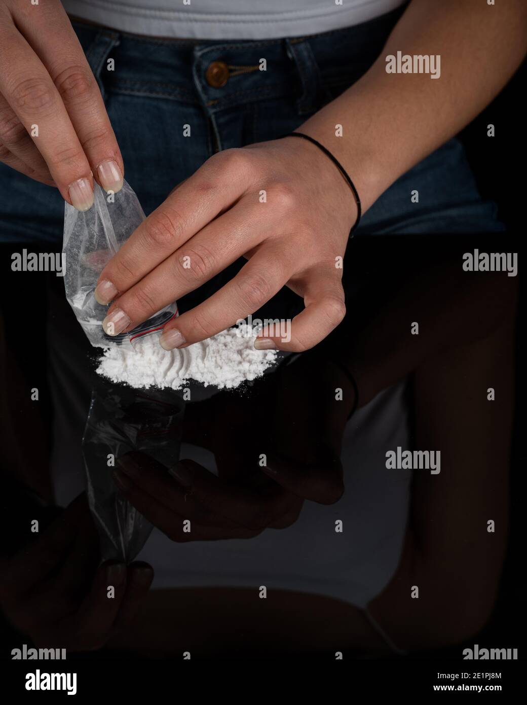 La donna tossicodipendente si sta preparando a russare la polvere di cocaina con la banconota da dollaro arrotolata. Concetto di stupefacenti. Primo piano della macro. Shot verticale. Alta risoluzione Foto Stock