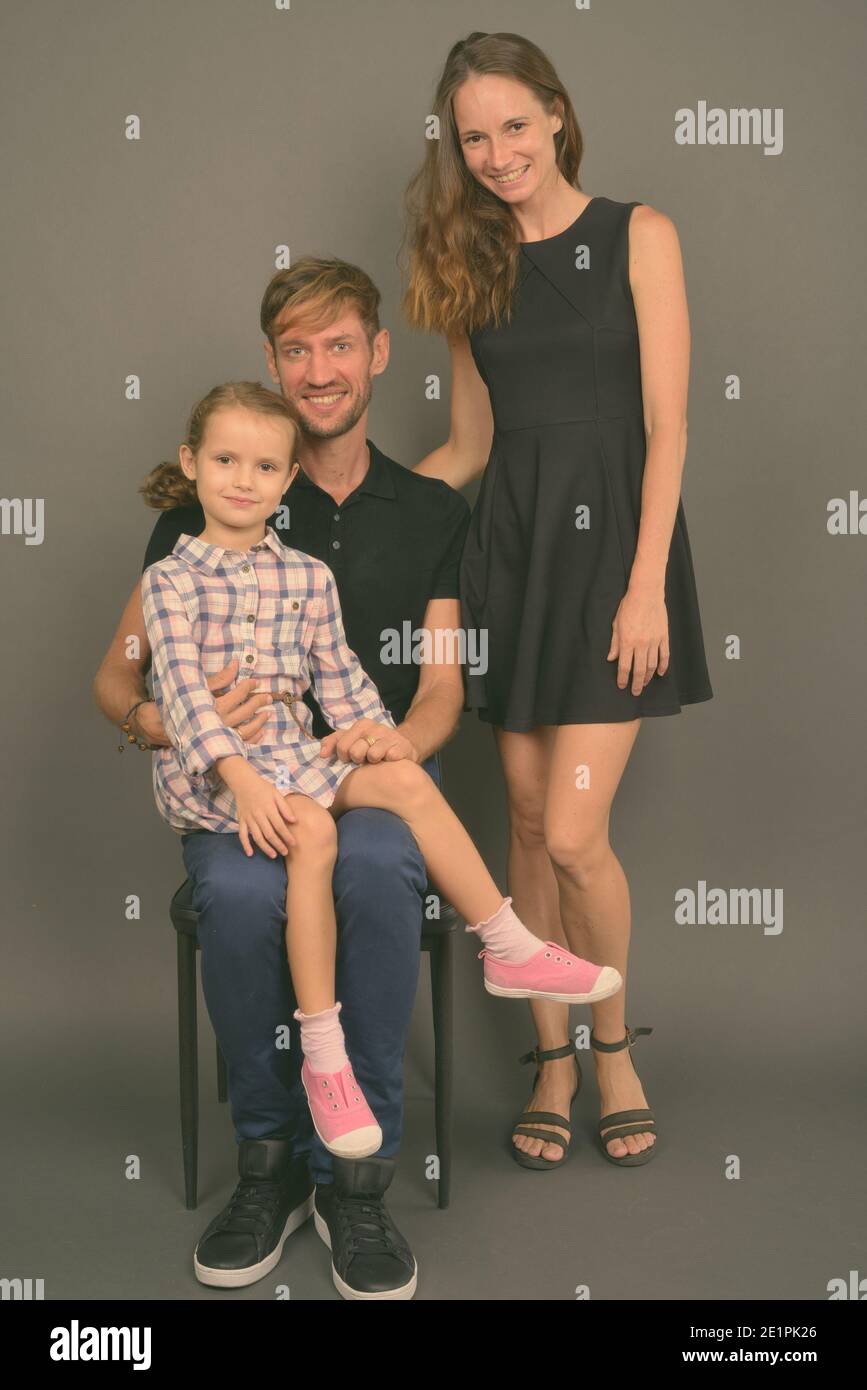 Giovane famiglia felice legare insieme contro lo sfondo grigio Foto Stock