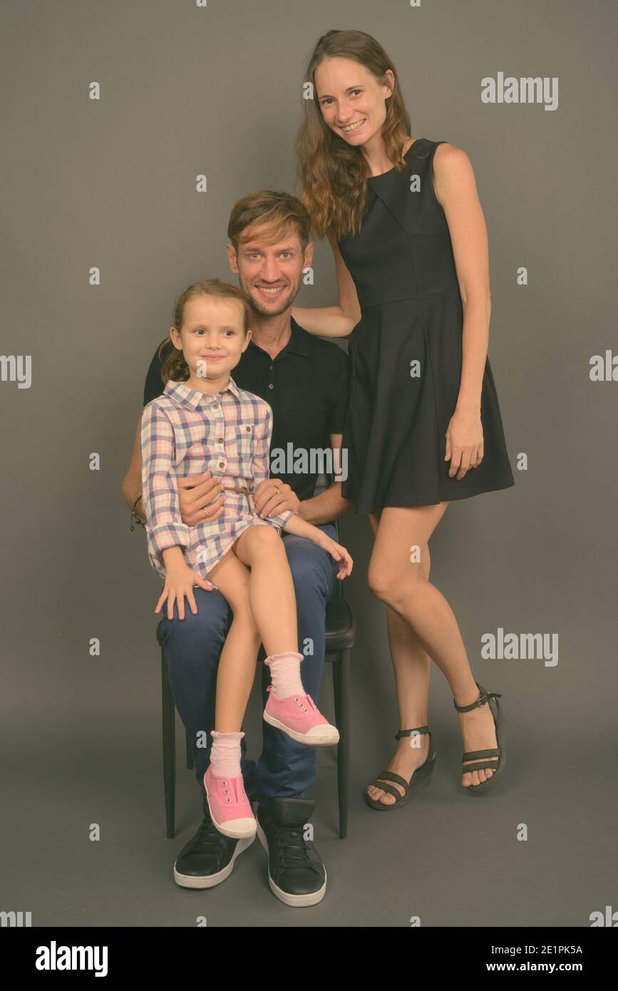 Giovane famiglia felice legare insieme contro lo sfondo grigio Foto Stock