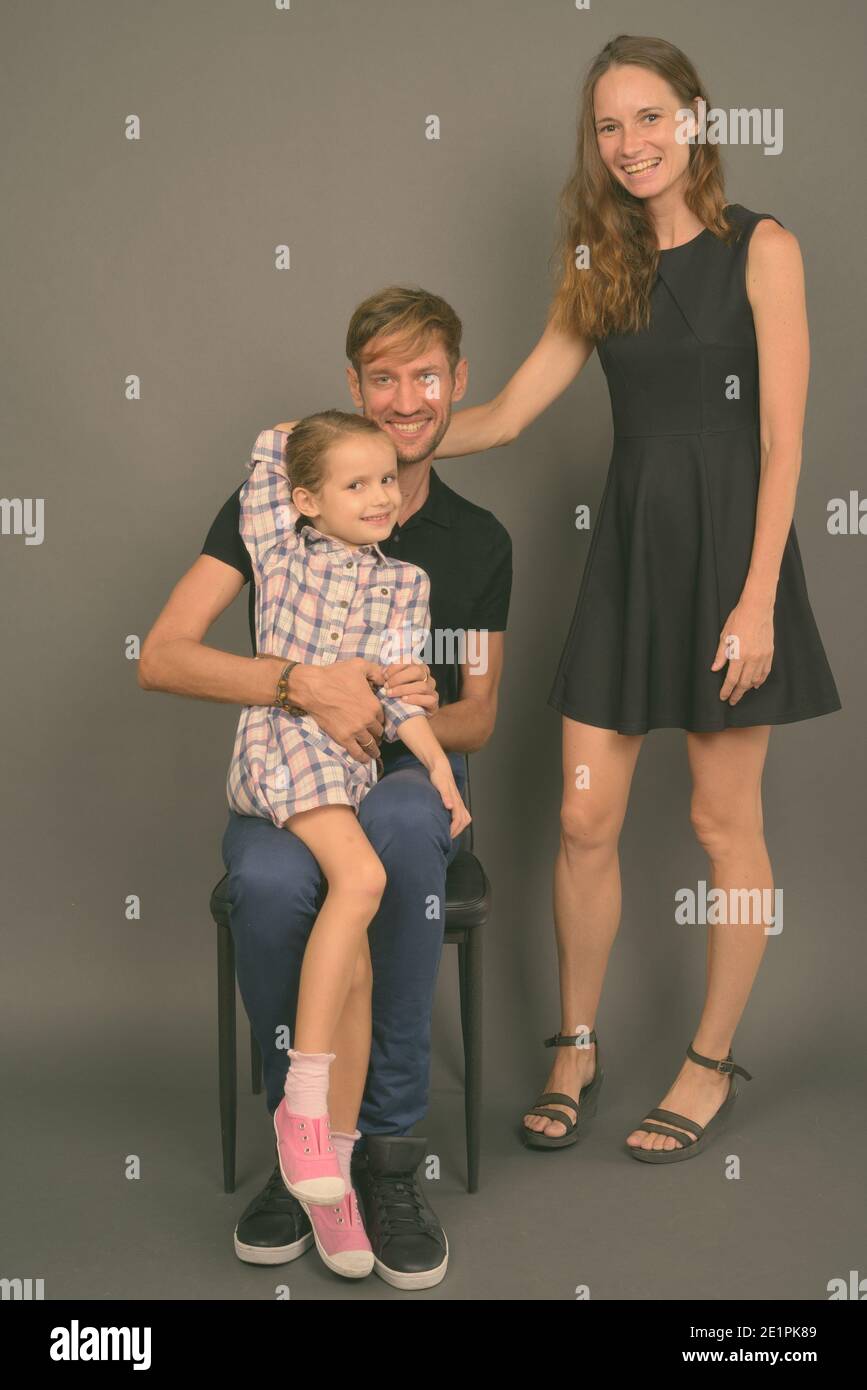 Giovane famiglia felice legare insieme contro lo sfondo grigio Foto Stock