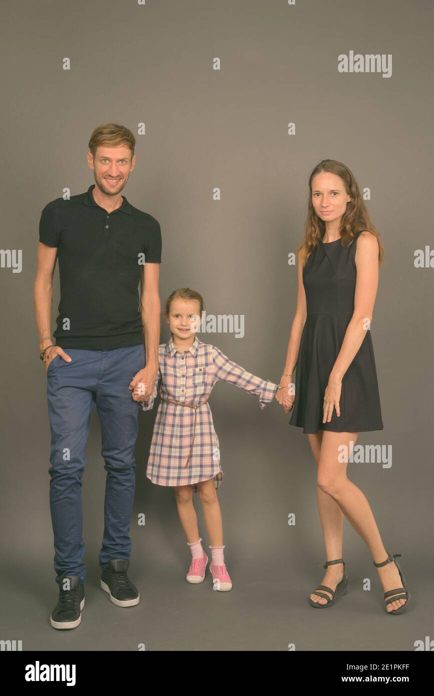 Giovane famiglia felice legare insieme contro lo sfondo grigio Foto Stock