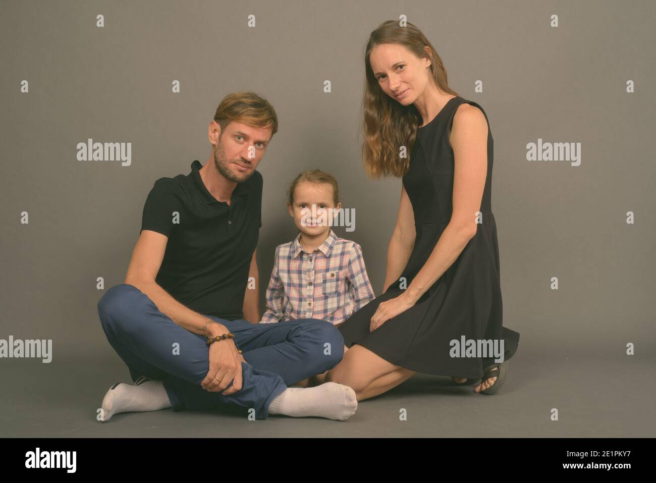 Giovane famiglia felice legare insieme contro lo sfondo grigio Foto Stock