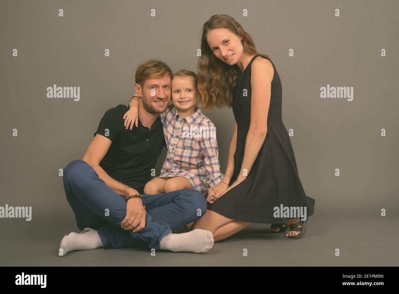 Giovane famiglia felice legare insieme contro lo sfondo grigio Foto Stock