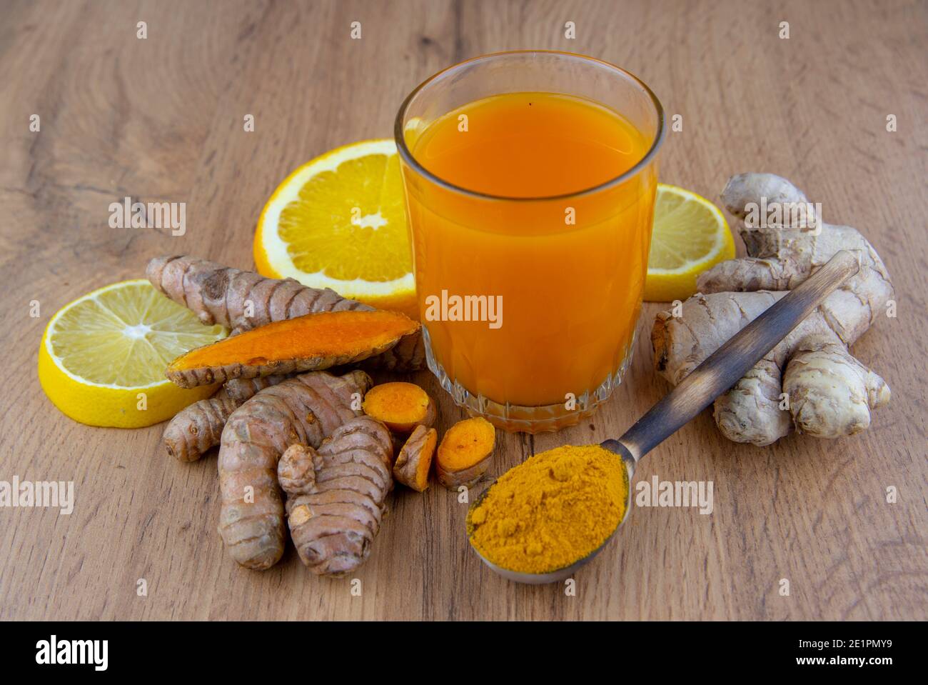 Un bicchiere di cocktail vitaminico, radice curcuma fresca su fondo grigio. Foto Stock