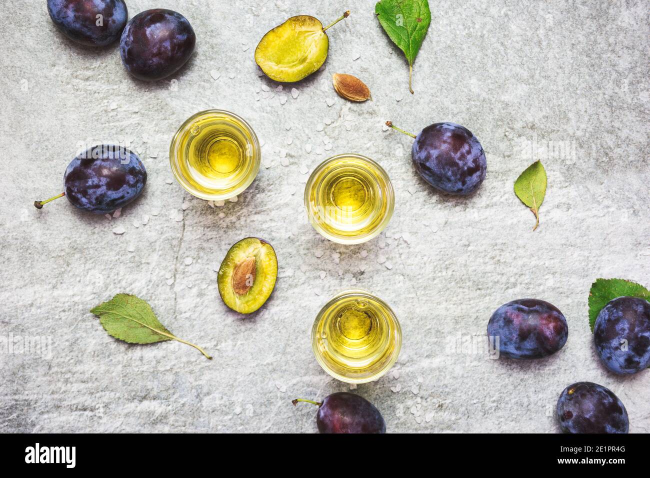 Rakija, raki o rakia è un tipo di brandy di bevanda alcolica forte balcanica a base di frutta fermentata. Rachia di prugne sul tavolo grigio con soni, vista dall'alto. Foto Stock