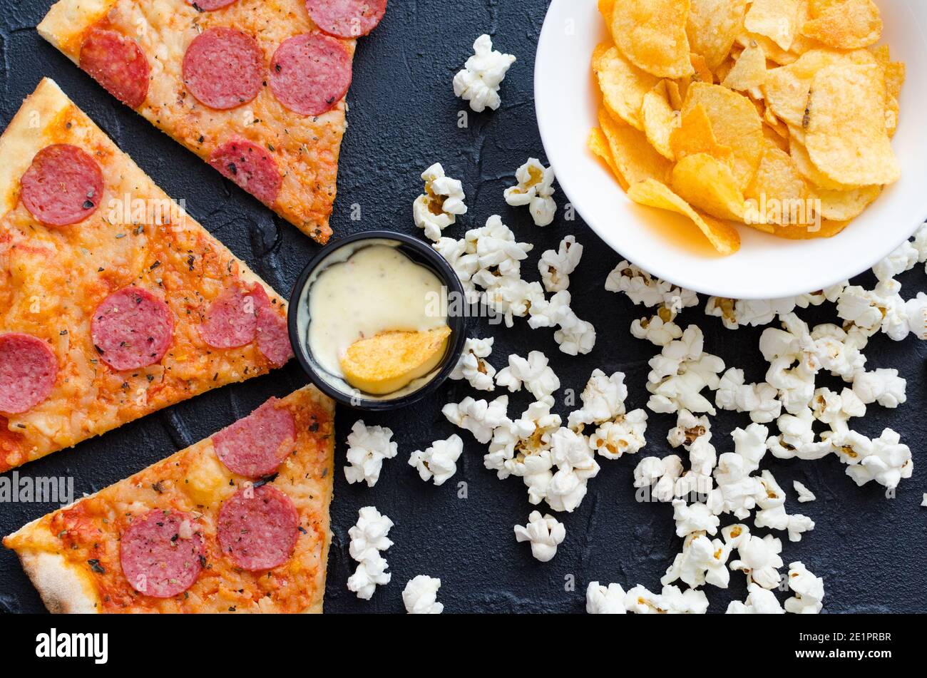 Fast food e concetto di cibo malsano. Primo piano di spuntini fast food: Pizza, popcorn e patatine. Assortimento di prodotti carboidrati cattivo per fichi Foto Stock