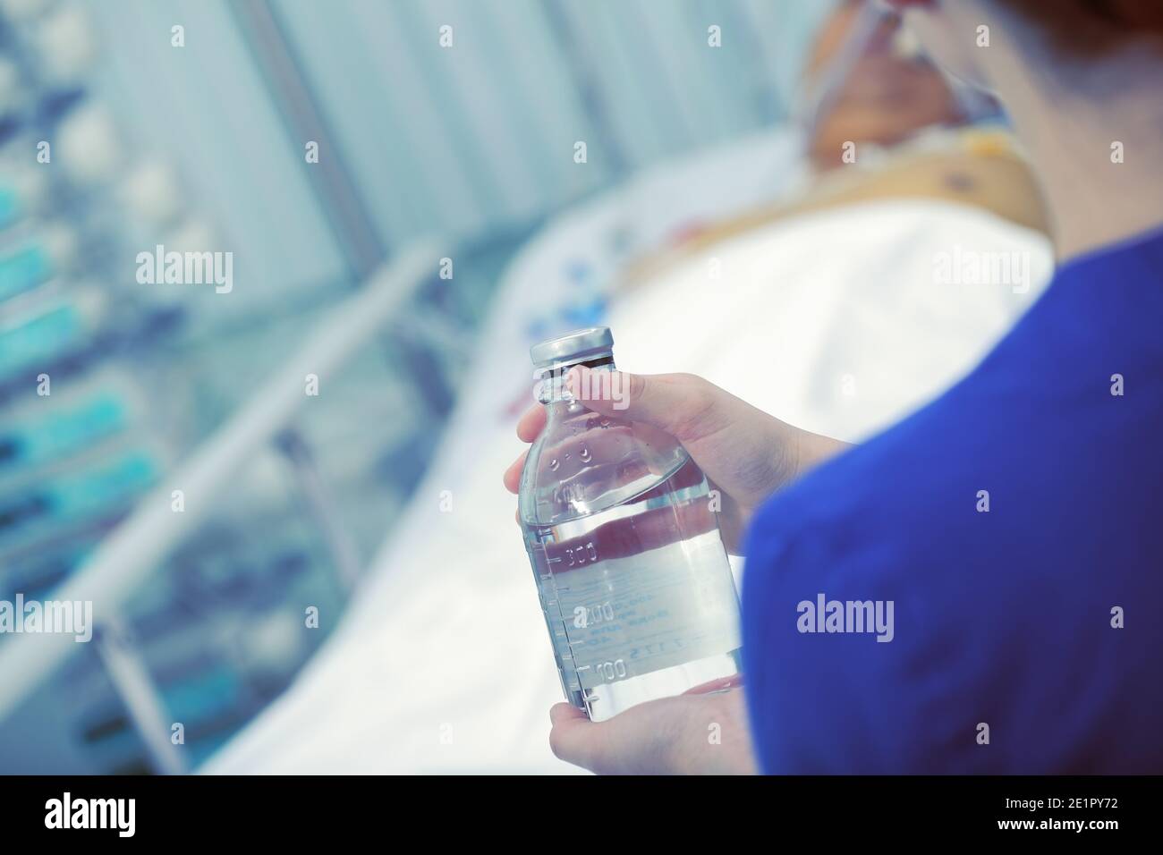 Flacone di medicinale nella mano dell'infermiere vicino al letto del paziente. Foto Stock