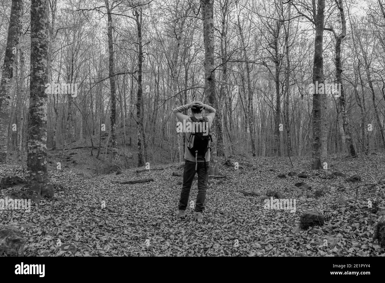 Uomo con zaino e mani in testa a piedi in Forest.Lost in natura, pericolo, solitario concept.tristezza e depressione stile di vita outdoors.Black e bianco Foto Stock