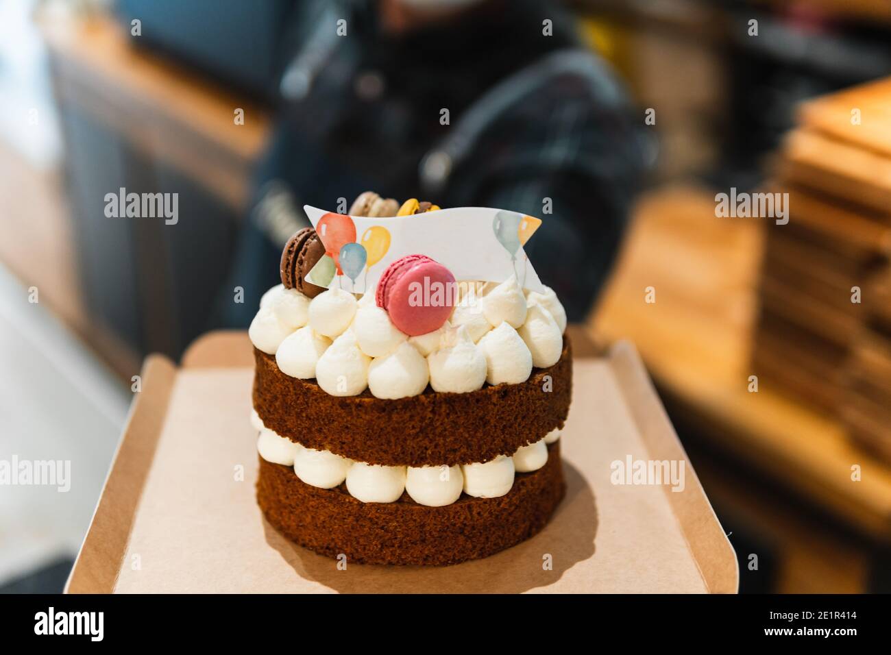Torta di compleanno tenuta da un panettiere in una panetteria. Il panettiere è fuori fuoco Foto Stock
