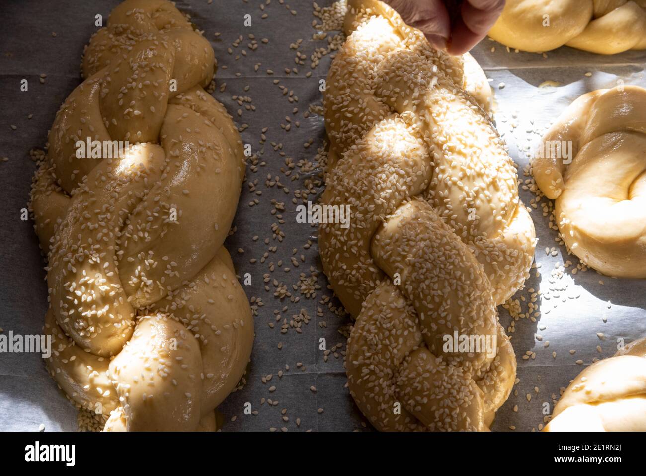 Cottura del pane sfidante fatto in casa. Una treccia con semi di sesamo in una padella prima della cottura. L'impasto soffiato prima della cottura. Foto di alta qualità Foto Stock