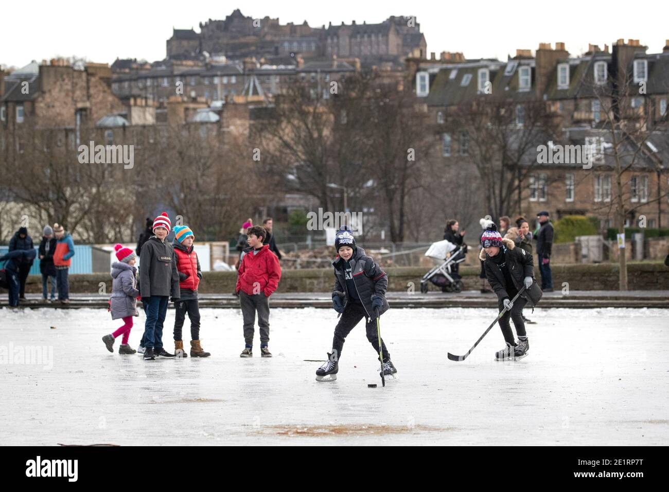 I bambini giocano a hockey su ghiaccio sul laghetto ghiacciato di Inverleith Park, Edimburgo. Foto Stock