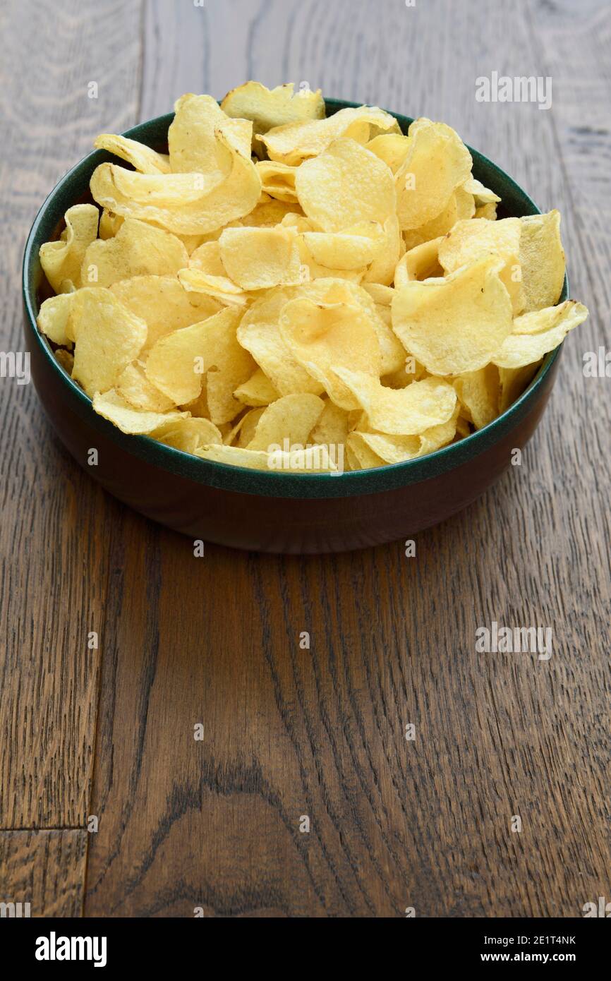 Ampia ciotola in legno con snack croccante al pezzetto di patate tavole di legno duro Foto Stock
