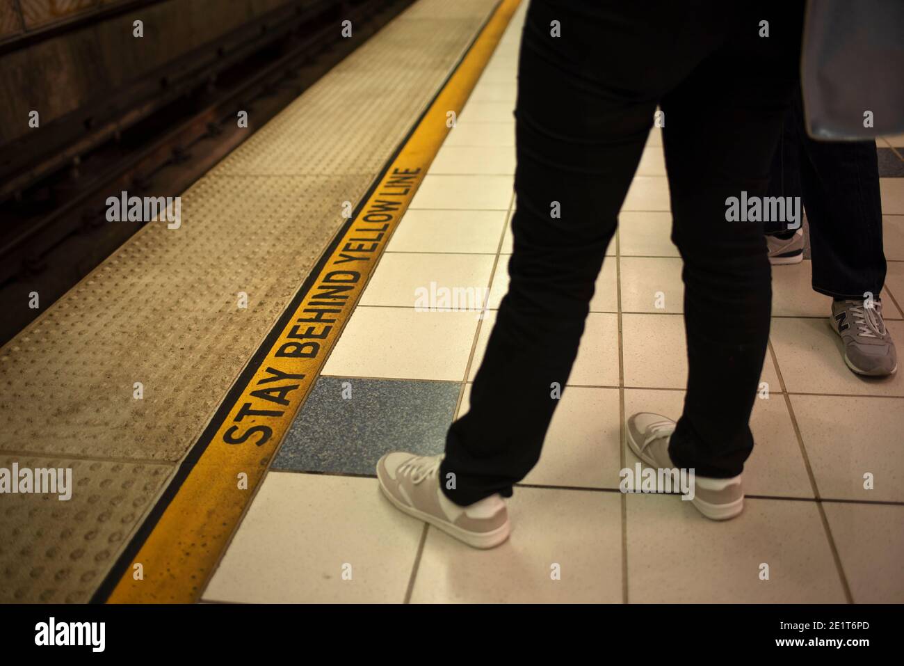 Persone in attesa del treno con 'Stay Behind Yellow Line' avvertimento in Metro, Los Angeles, CA, USA. Foto Stock