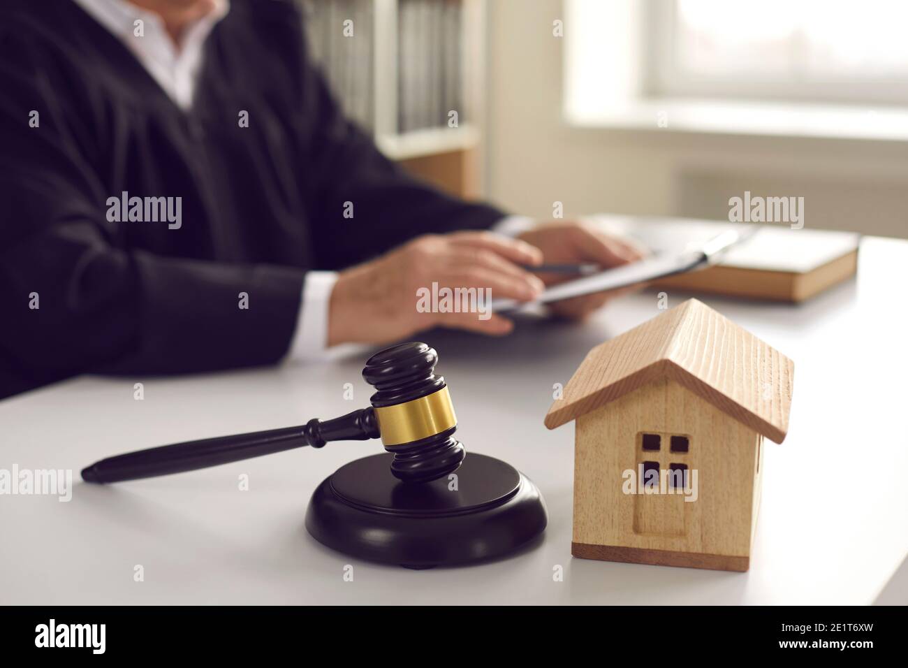 Gavel sul blocco sonoro e casa giocattolo sul tavolo del giudice in aula durante l'audizione Foto Stock