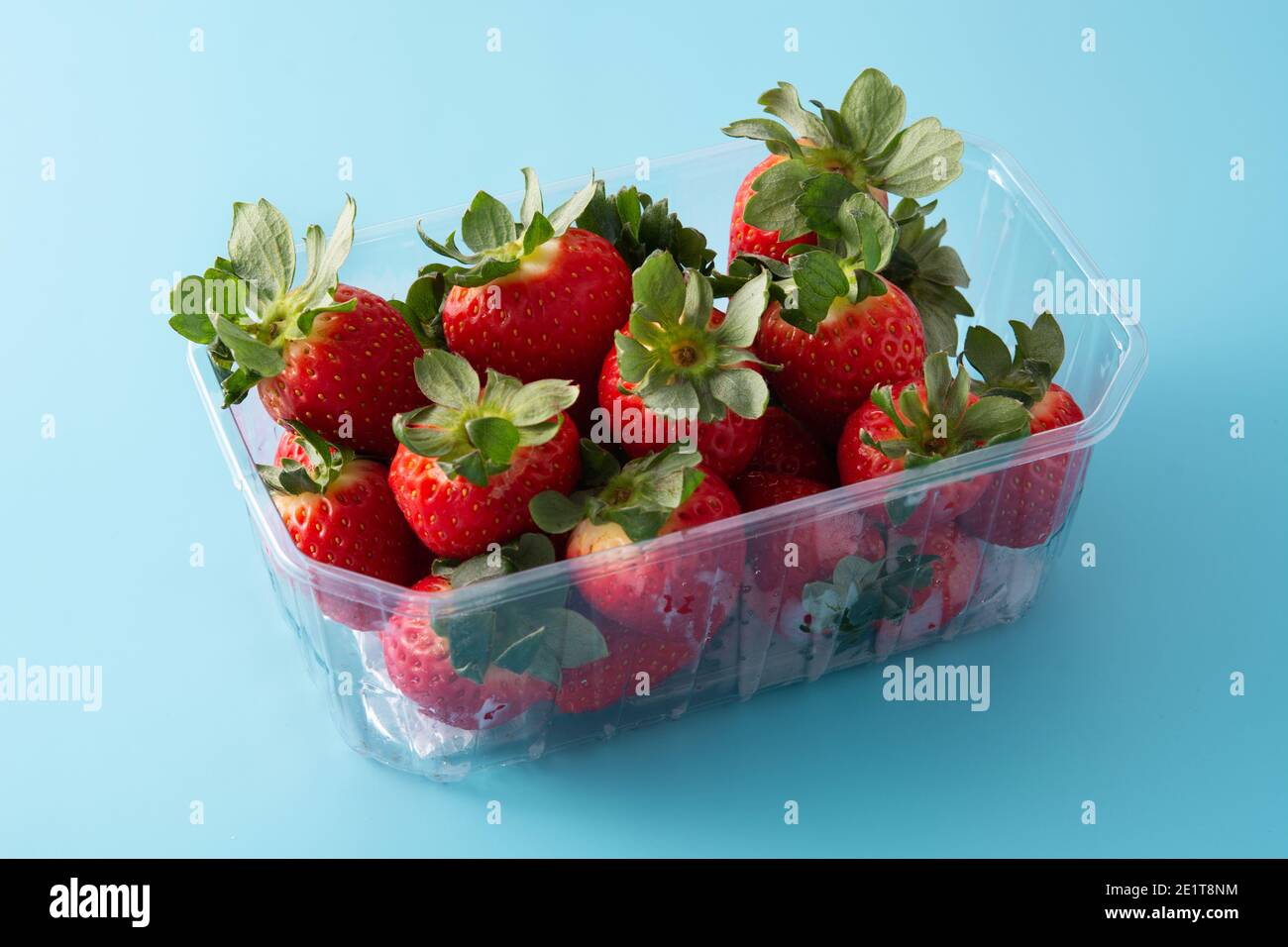 Fragole in confezione di plastica su sfondo blu Foto Stock