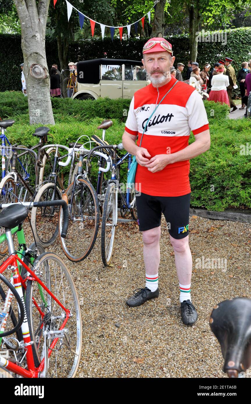 Visitatore del Goodwood Revival, Regno Unito, vestito in abiti da ciclisti d'epoca. Outfit da corsa retrò. COME logo Gillott Foto Stock