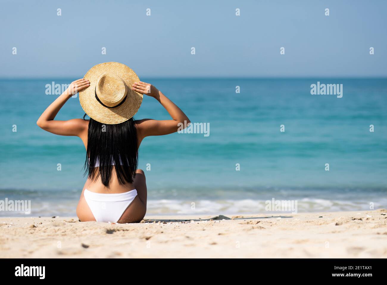 Donna in bikini in appoggio sulla spiaggia nel cappello di paglia Foto  stock - Alamy