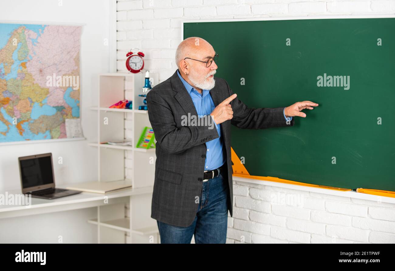 insegnante senior spiegare il soggetto alla lavagna. insegnante di geografia. classe con mappa. torna a scuola. istruzione nella scuola moderna. uomo bearded mostra qualcosa. copia spazio. Foto Stock